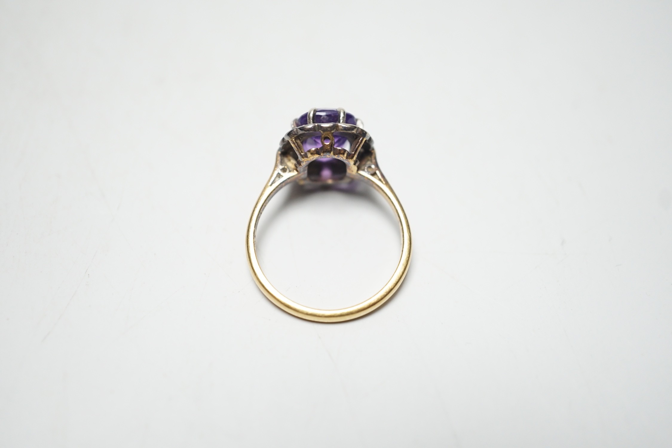 An 18ct, amethyst and diamond set oval cluster ring, size P, gross weight 4.5 grams.